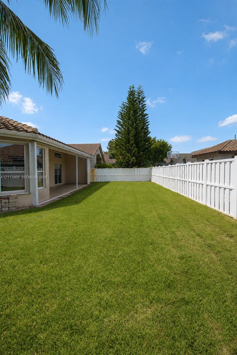 Expansive backyard featuring a level lawn, covered patio, and perimeter white vinyl privacy fencing Expansive backyard featuring a level lawn, covered patio, and perimeter white vinyl privacy fencing