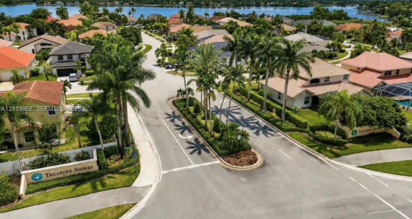 Aerial perspective of the Treasure Shores community entrance featuring a landscaped center median, palm tree-lined streets, and a waterfront position Aerial perspective of the Treasure Shores community entrance featuring a landscaped center median, palm tree-lined streets, and a waterfront position