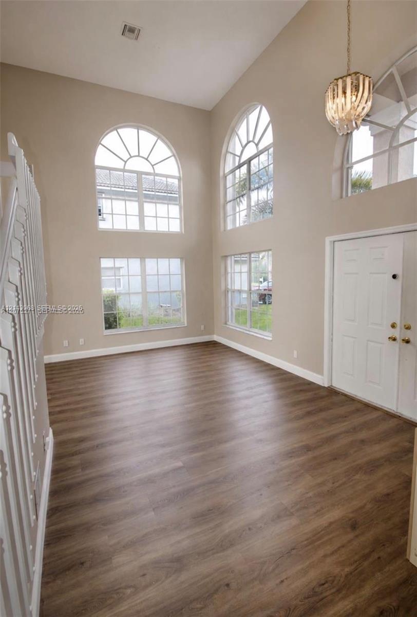 Double-height ceiling, wood-finish flooring, multi-pane arched windows, and decorative tiered pendant lighting Double-height ceiling, wood-finish flooring, multi-pane arched windows, and decorative tiered pendant lighting