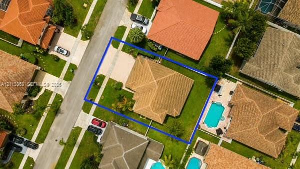 Aerial perspective of property featuring a multi-pitched shingle roof, concrete driveway, and expansive corner lot with mature landscaping Aerial perspective of property featuring a multi-pitched shingle roof, concrete driveway, and expansive corner lot with mature landscaping