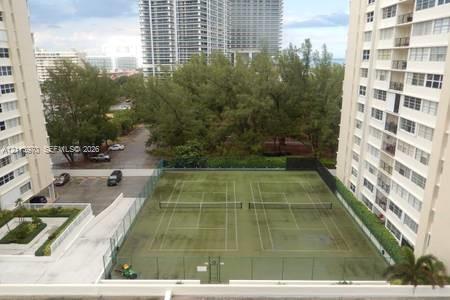 Dual tennis courts with chain-link fencing and mature tree landscaping Dual tennis courts with chain-link fencing and mature tree landscaping