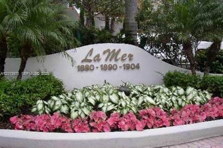 Curved concrete signage monument featuring metallic lettering, complemented by tiered landscaping including mature palm trees and flowering tropical vegetation Curved concrete signage monument featuring metallic lettering, complemented by tiered landscaping including mature palm trees and flowering tropical vegetation