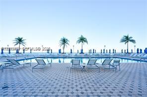 Swimming pool with a tile-patterned deck and perimeter palm trees Swimming pool with a tile-patterned deck and perimeter palm trees