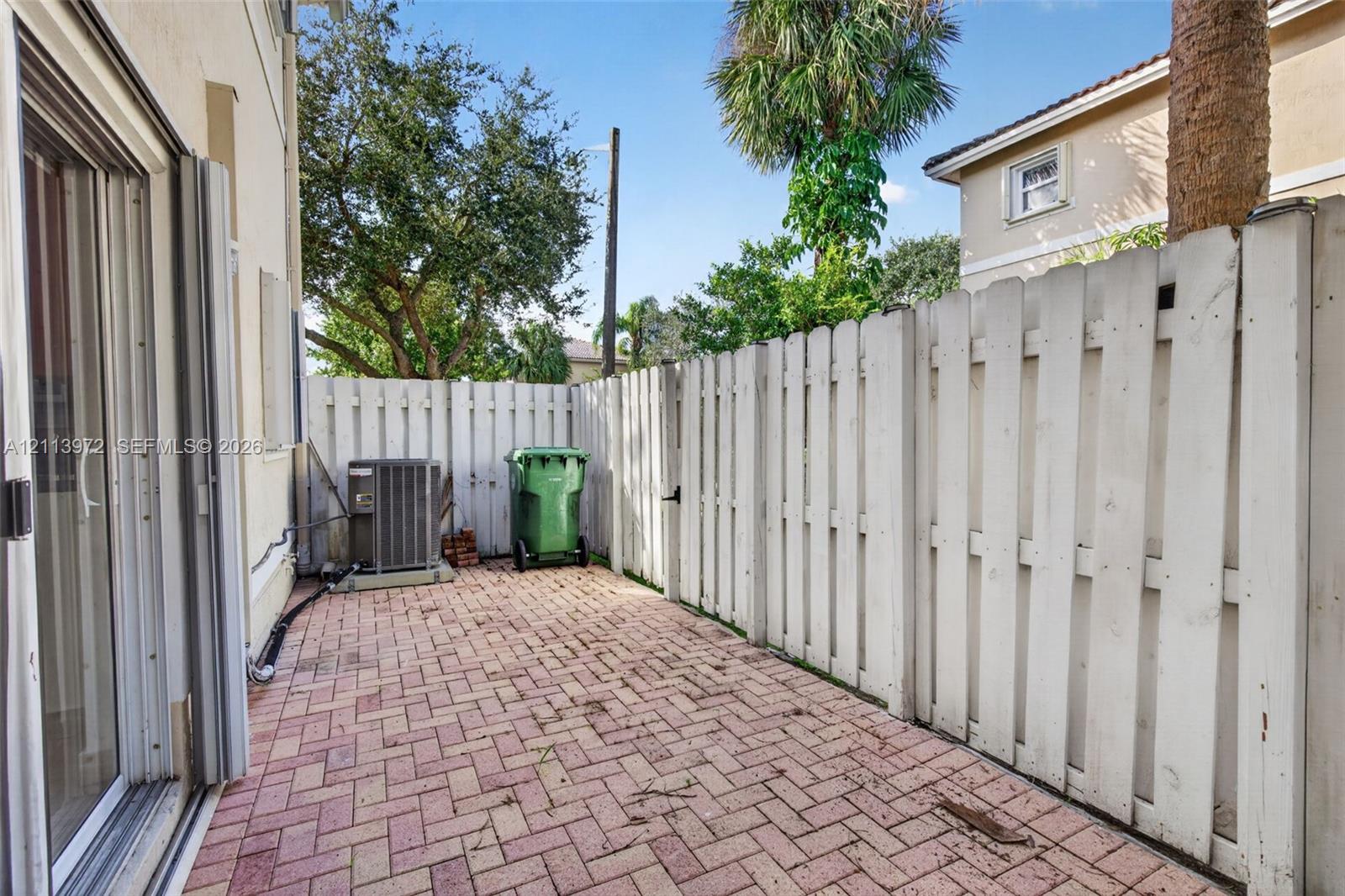 Private outdoor area featuring brick-paver flooring and a white wood-picket fence
