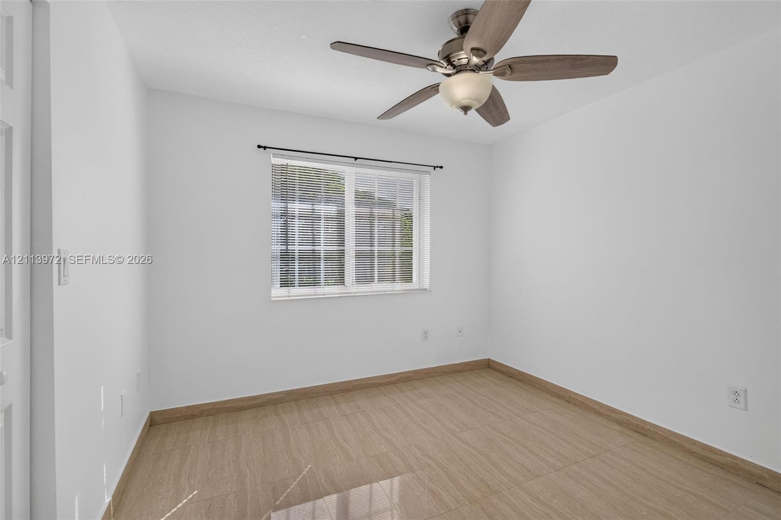 Room featuring wood-finish tile flooring, neutral wall tones, a multi-blade ceiling fan with integrated lighting, and a single-hung window