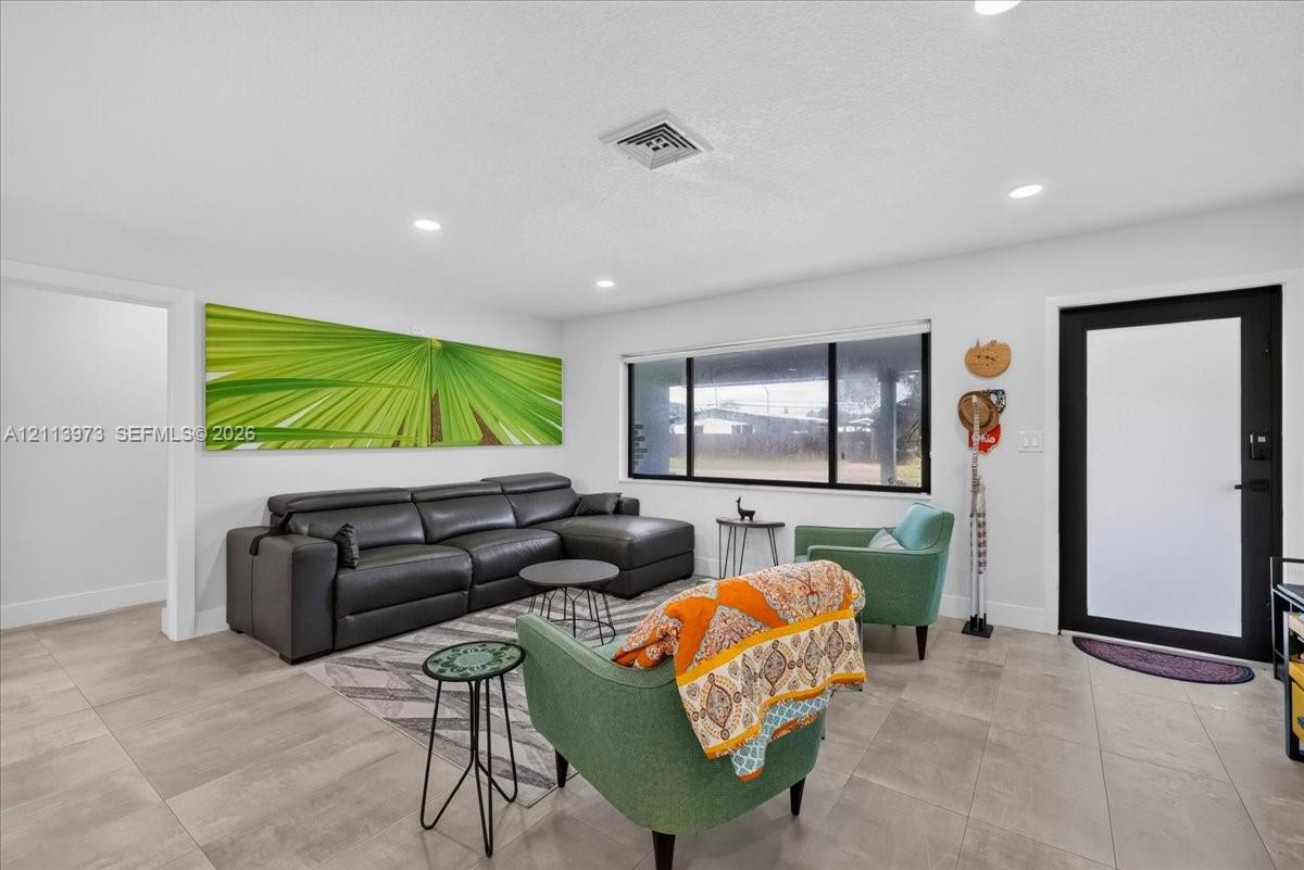 Neutral-toned large format tile flooring, recessed lighting, and a modern entry door featuring a matte black frame with frosted glass Neutral-toned large format tile flooring, recessed lighting, and a modern entry door featuring a matte black frame with frosted glass