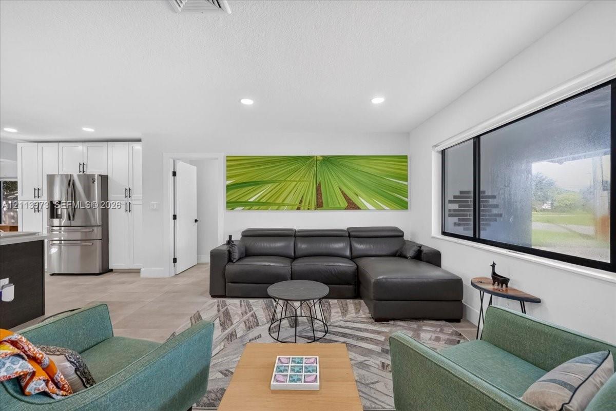 Open-concept interior featuring large-format tile flooring, recessed lighting, and expansive horizontal picture windows Open-concept interior featuring large-format tile flooring, recessed lighting, and expansive horizontal picture windows