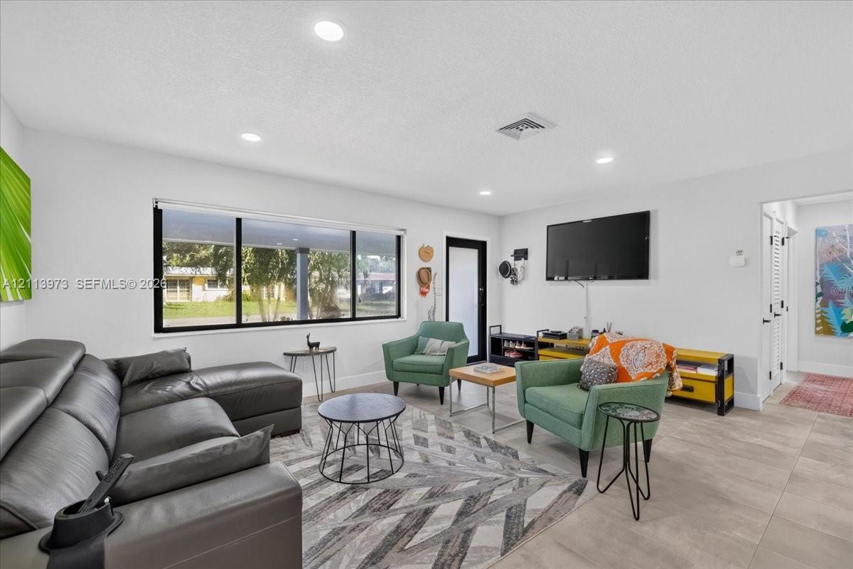 Living area featuring large format tile flooring, recessed lighting, and a picture window Living area featuring large format tile flooring, recessed lighting, and a picture window