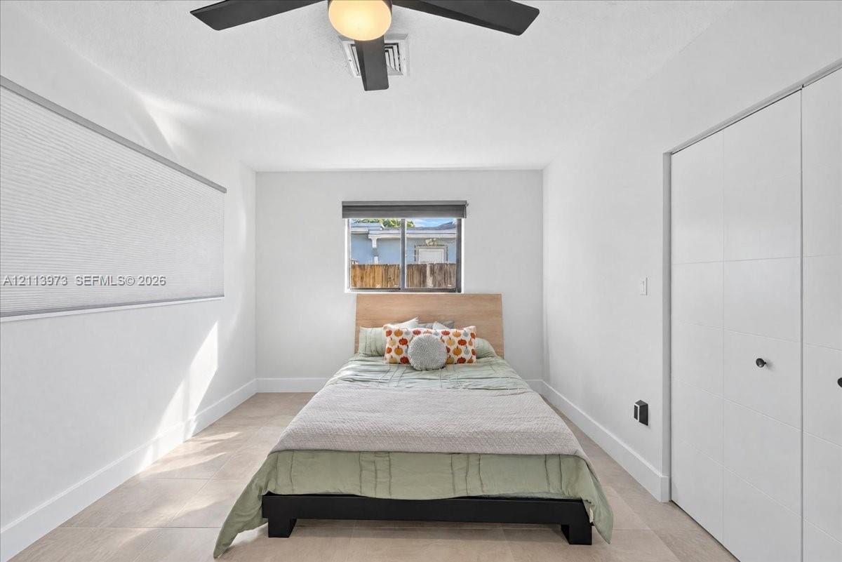 Neutral-toned tile flooring, white interior walls, ceiling fan with integrated lighting, and white multi-panel closet doors
