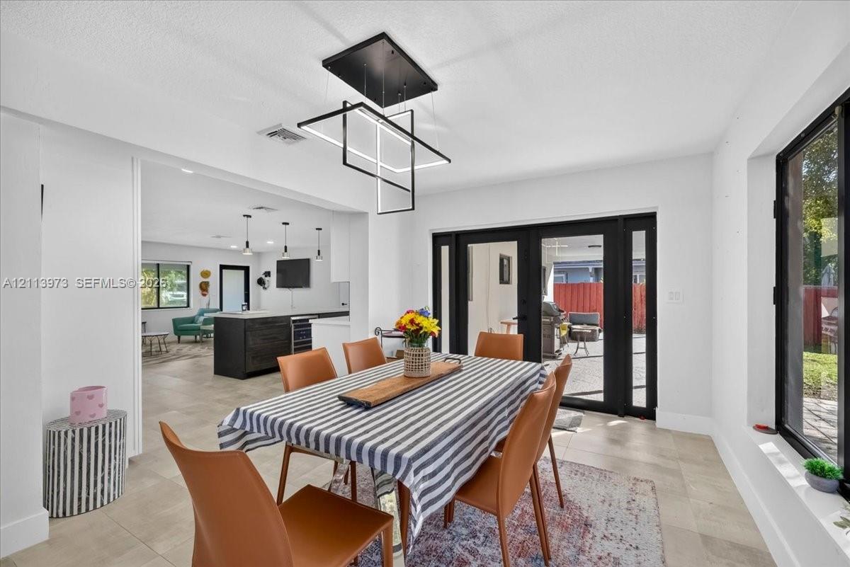Modern geometric pendant lighting, oversized ceramic tile flooring, and black-framed glass double doors
