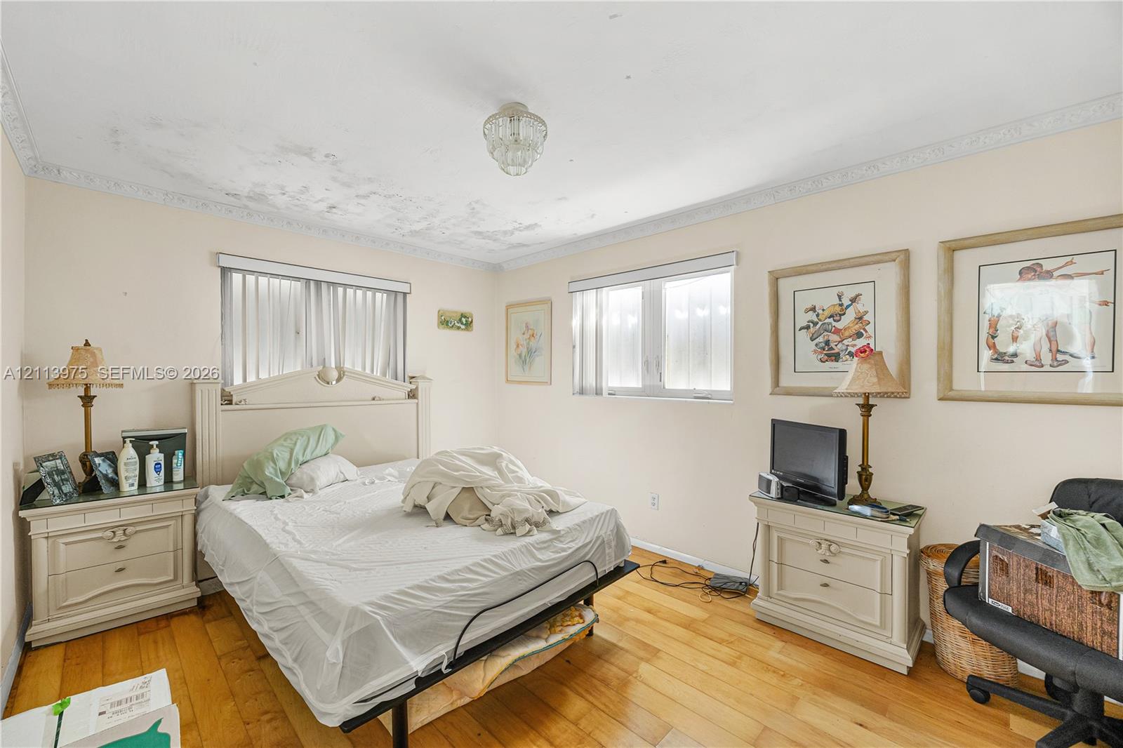 Bedroom featuring wood-finish flooring, crown molding, and two windows with blinds