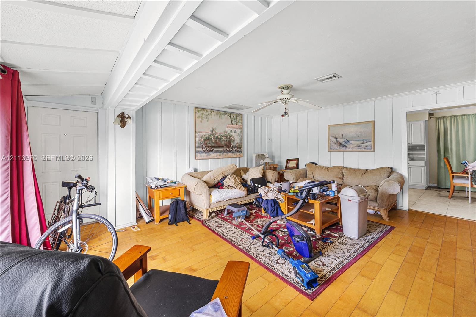 Interior featuring wood-finish flooring, vertical plank wall paneling, and a ceiling-mounted fan