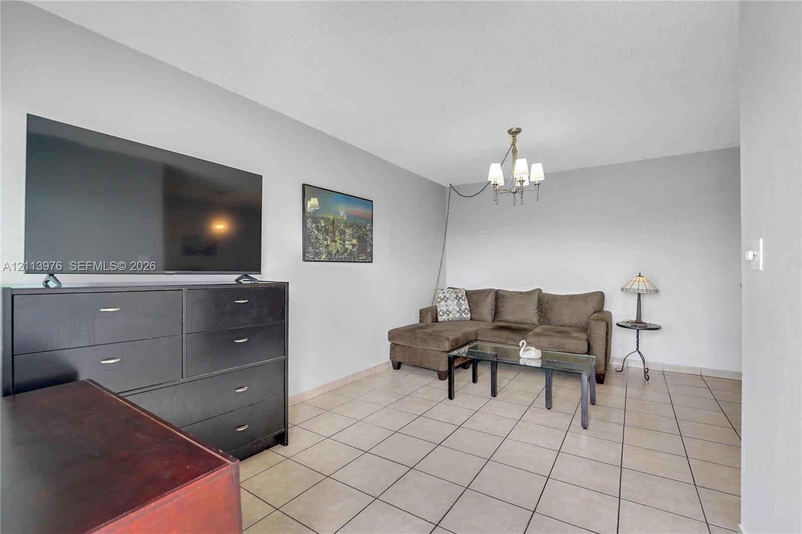 Neutral interior featuring ceramic tile flooring and a multi-arm metallic chandelier with frosted glass shades