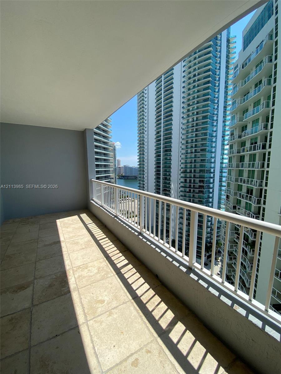 Covered balcony featuring stone-finish flooring and a white metal railing