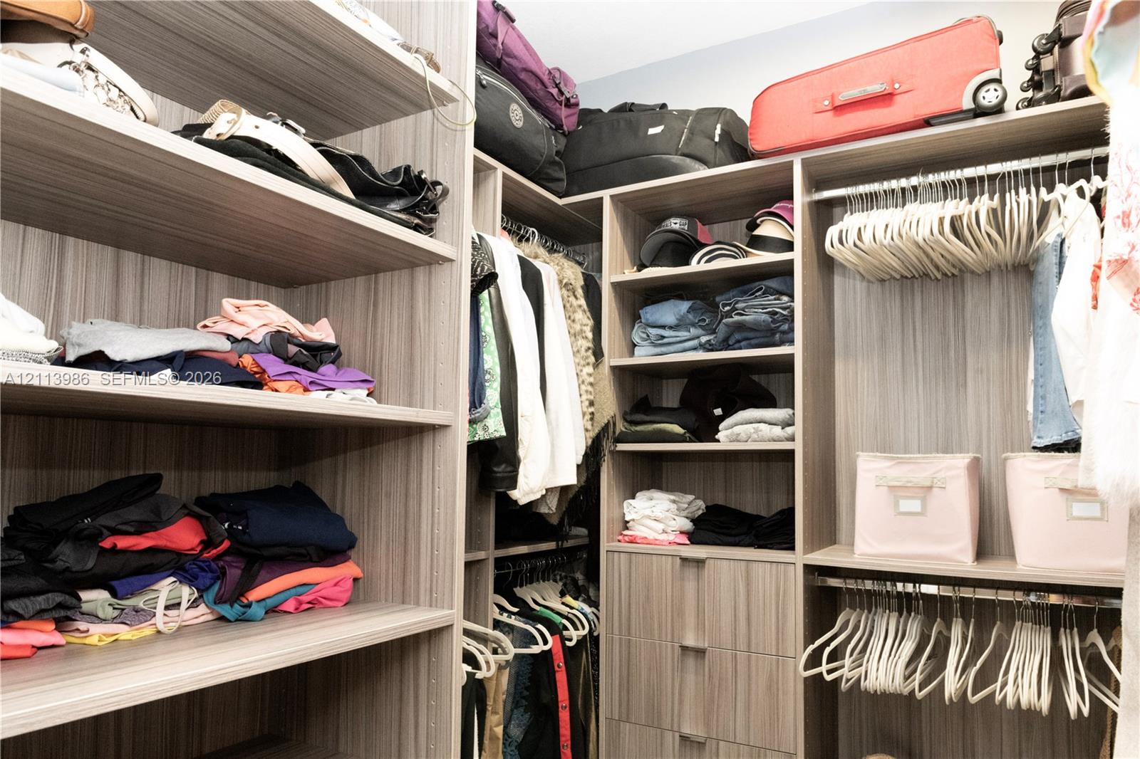 Walk-in closet system featuring custom wood-finish shelving, integrated clothing rods, and built-in drawer storage