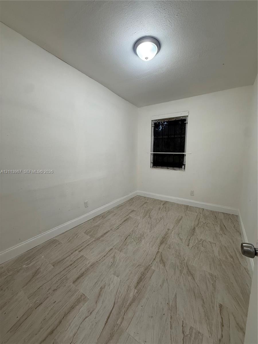 Neutral-toned wood-finish flooring, white walls, and a single-light flush mount ceiling fixture
