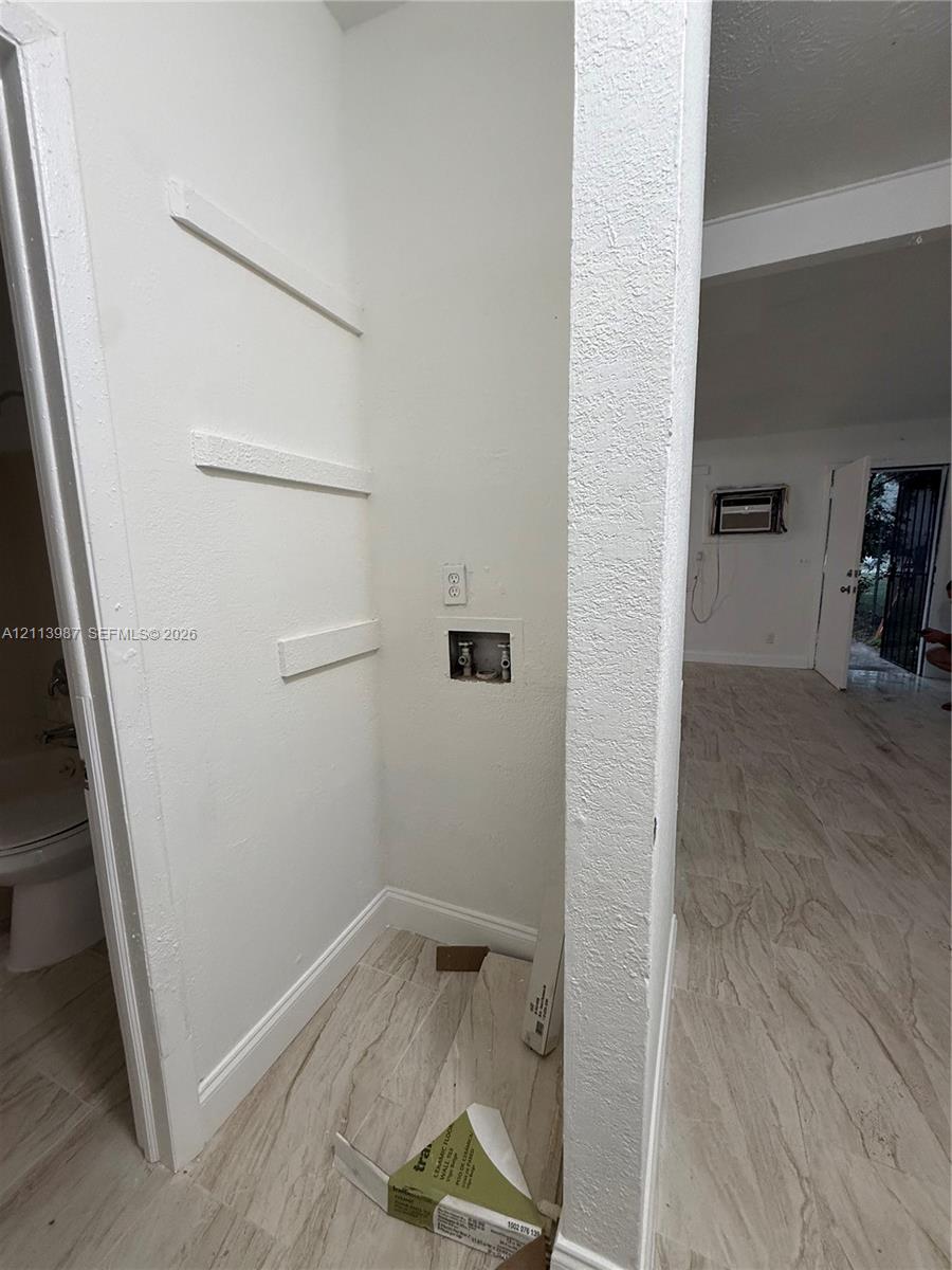 Dedicated laundry nook featuring wood-finish flooring, built-in shelving, and utility hookups Dedicated laundry nook featuring wood-finish flooring, built-in shelving, and utility hookups
