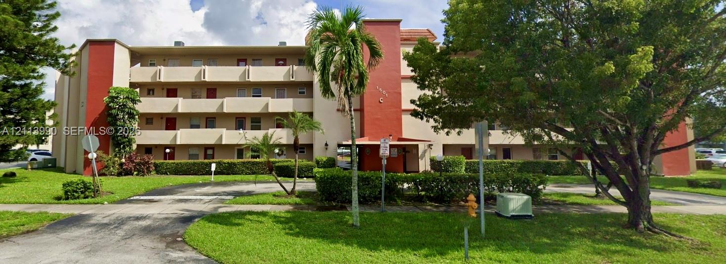 Multi-story building featuring stucco exterior, integrated private balconies, and landscaped grounds with mature trees and palms Multi-story building featuring stucco exterior, integrated private balconies, and landscaped grounds with mature trees and palms