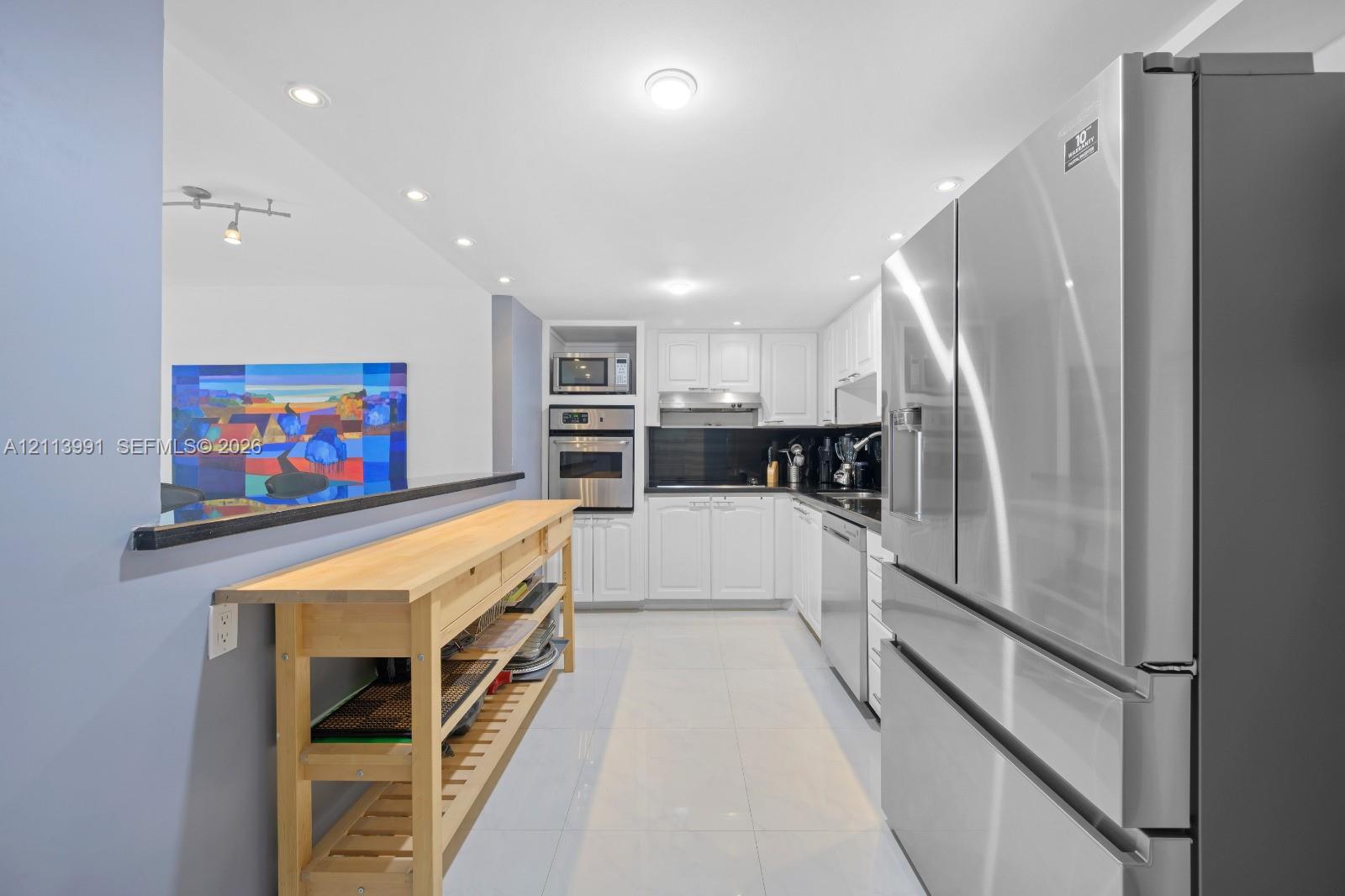Kitchen featuring white cabinetry, stone-finish countertops, stainless steel appliances, built-in wall oven and microwave, and recessed lighting
