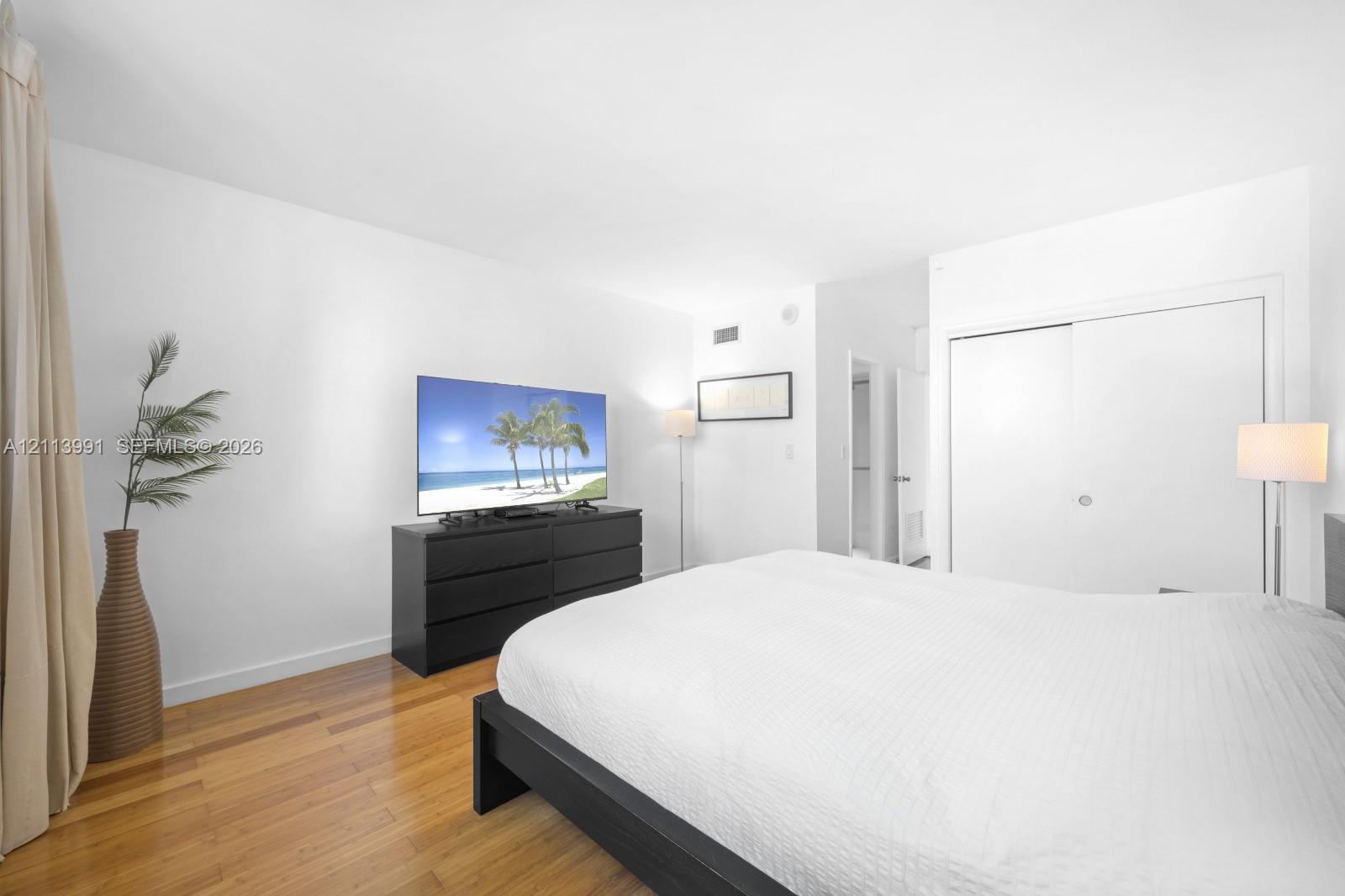 Room featuring wood-finish flooring, white walls, and a sliding-door closet