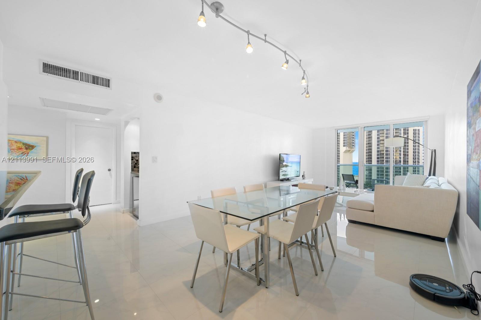 Open-concept area featuring polished tile flooring, track lighting, and floor-to-ceiling glass sliding doors