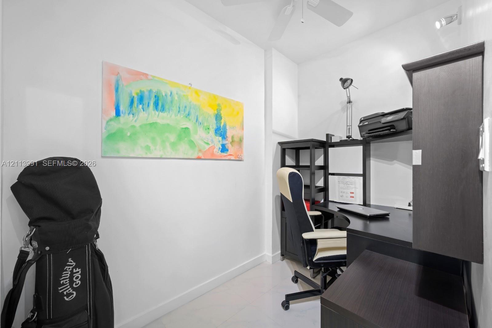 Neutral-toned interior space featuring light-reflective tile flooring, white walls, and a ceiling-mounted fan with integrated lighting