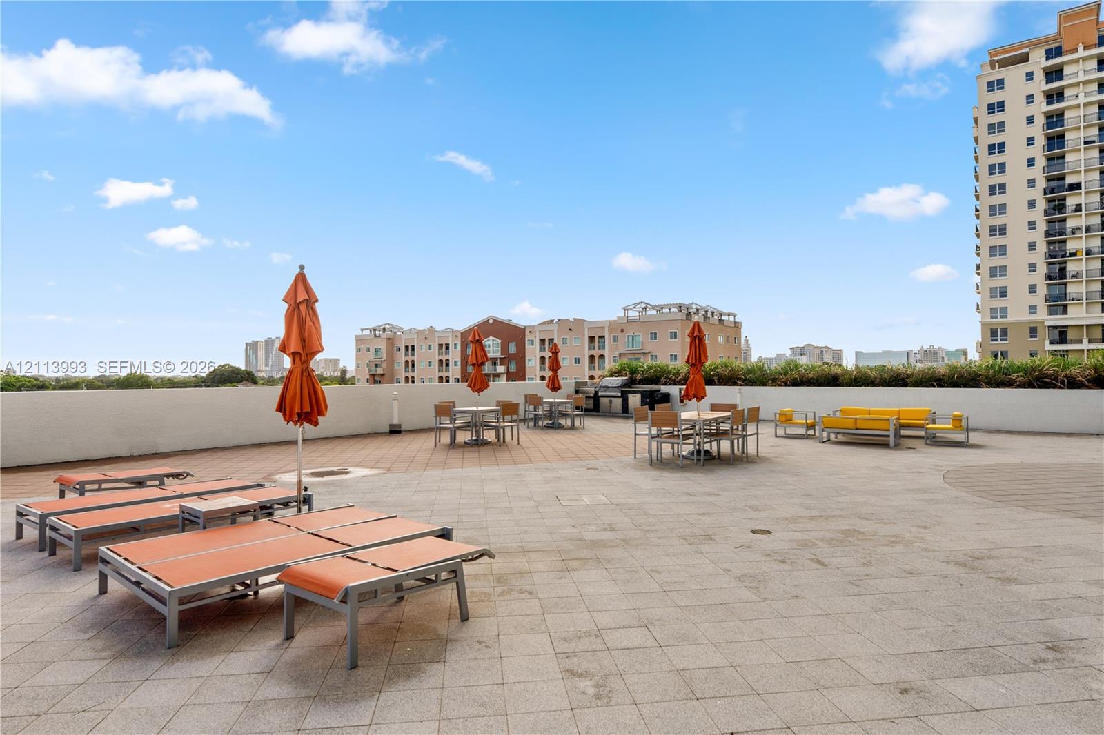 Expansive rooftop terrace featuring paved stone flooring, perimeter masonry walls, and a built-in outdoor cooking station