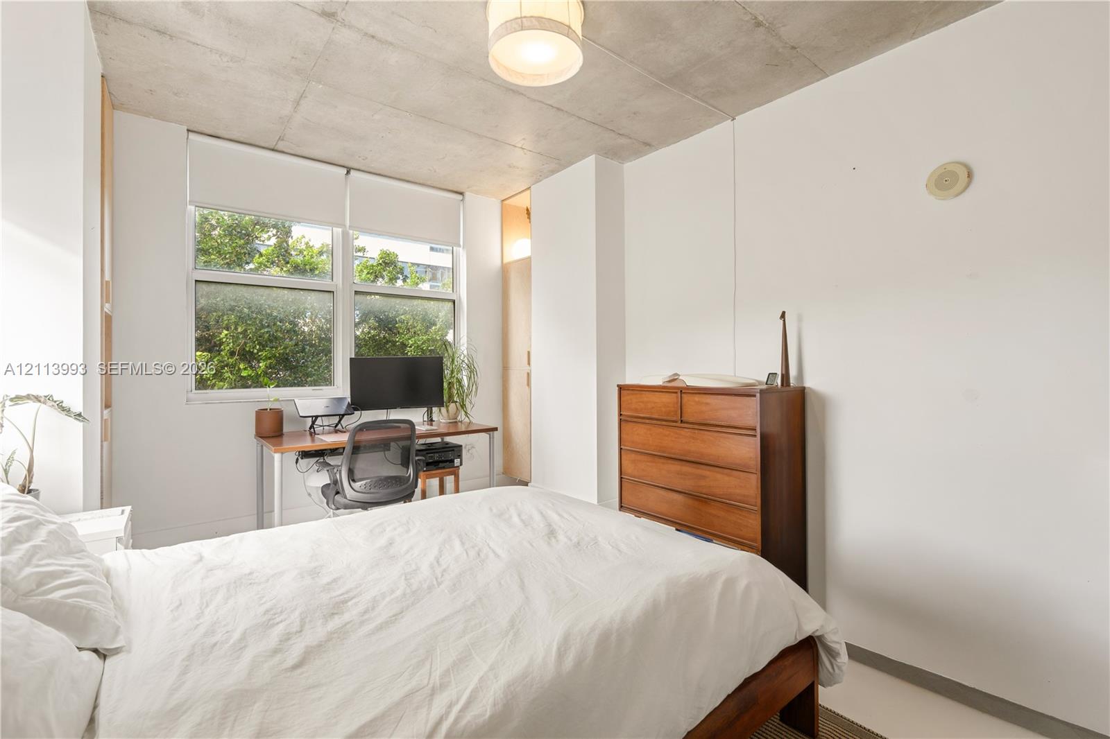 Exposed concrete ceiling, large multi-pane windows, and built-in closet cabinetry with wood-finish doors