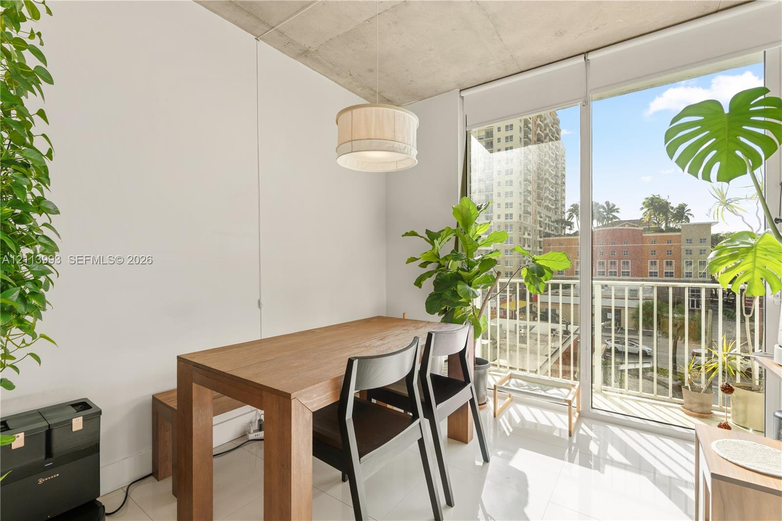 Exposed concrete ceiling, floor-to-ceiling glass door, polished tile flooring, and a drum-style pendant light fixture