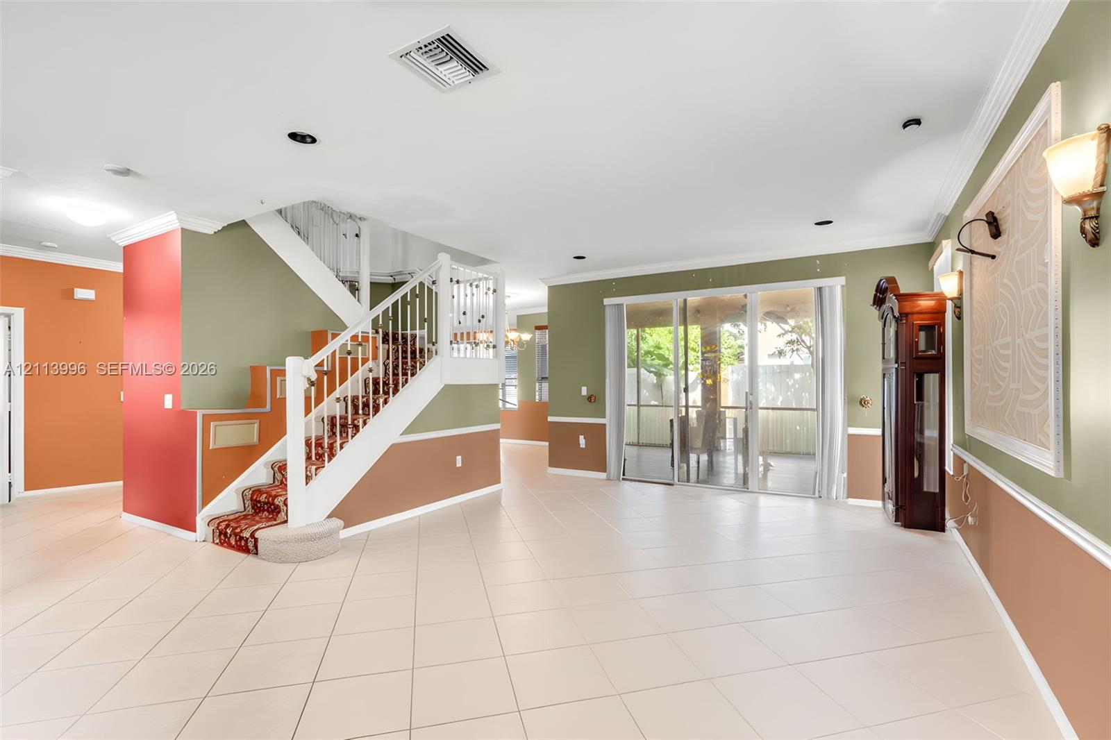 Open interior featuring ceramic tile flooring, a staircase with white balusters, sliding glass doors, and wall-mounted sconce lighting