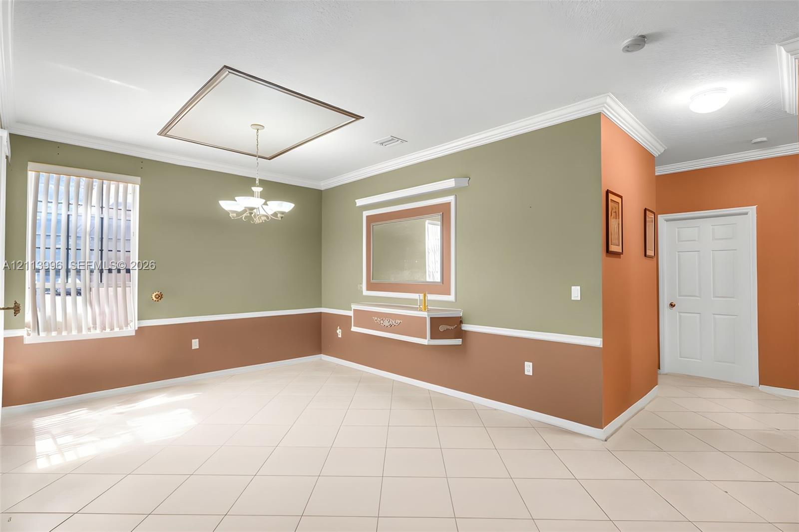Tile flooring, crown molding, chair rail trim, multi-tiered chandelier, and built-in wall niche with mirror