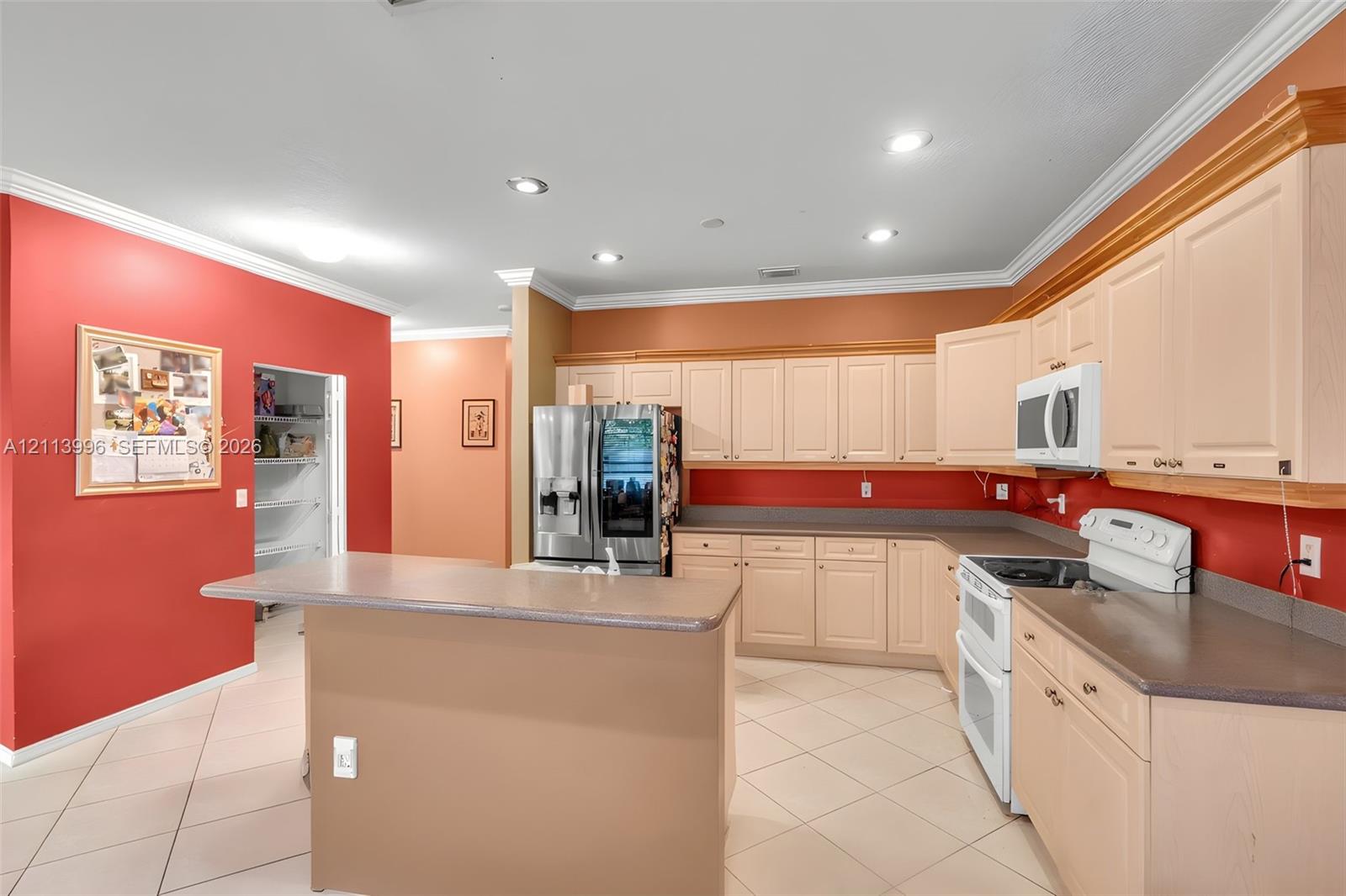 Kitchen featuring light-tone cabinetry, solid surface countertops, a walk-in pantry, recessed ceiling lighting, and ceramic tile flooring
