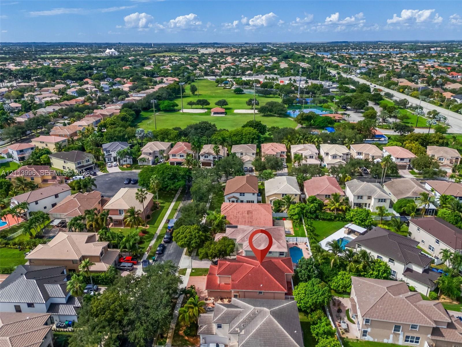 Aerial perspective featuring a multi-hipped clay tile roof, stucco exterior, and a private swimming pool