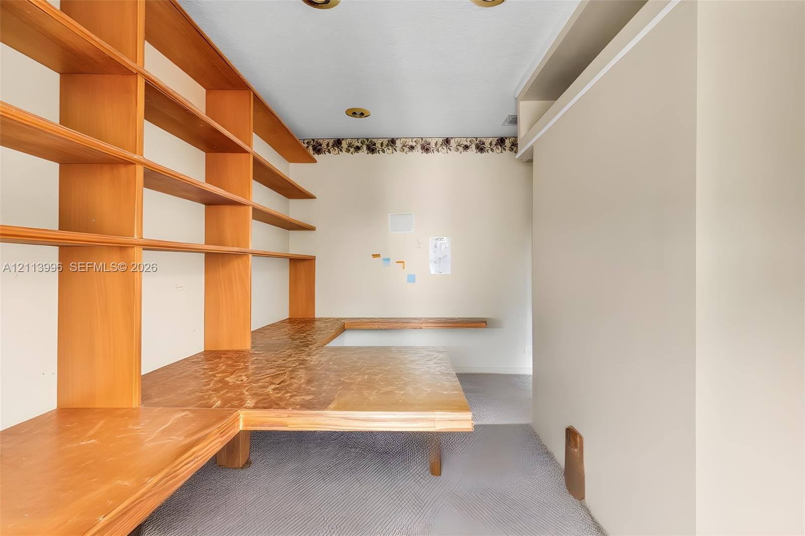 Built-in L-shaped wood cabinetry featuring floor-to-ceiling shelving and an integrated countertop surface