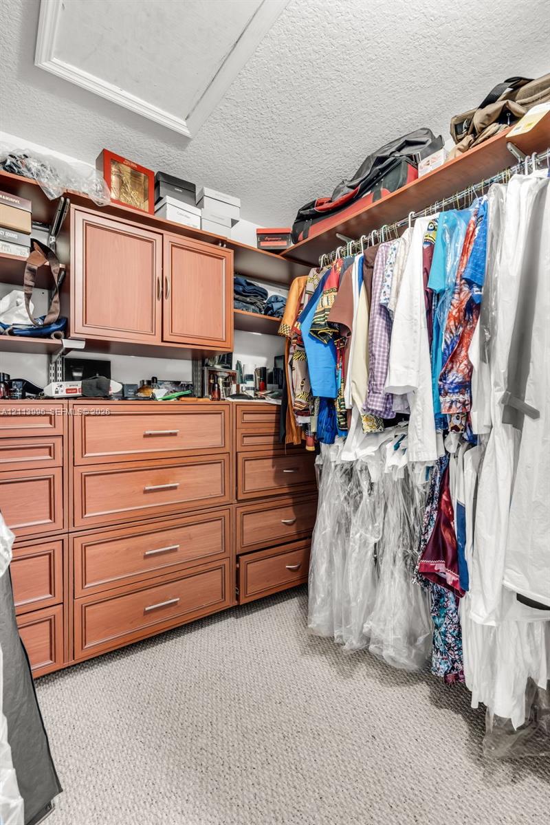 Custom storage system featuring wood-finish cabinetry, built-in shelving, integrated dresser drawers, and metal clothing rods