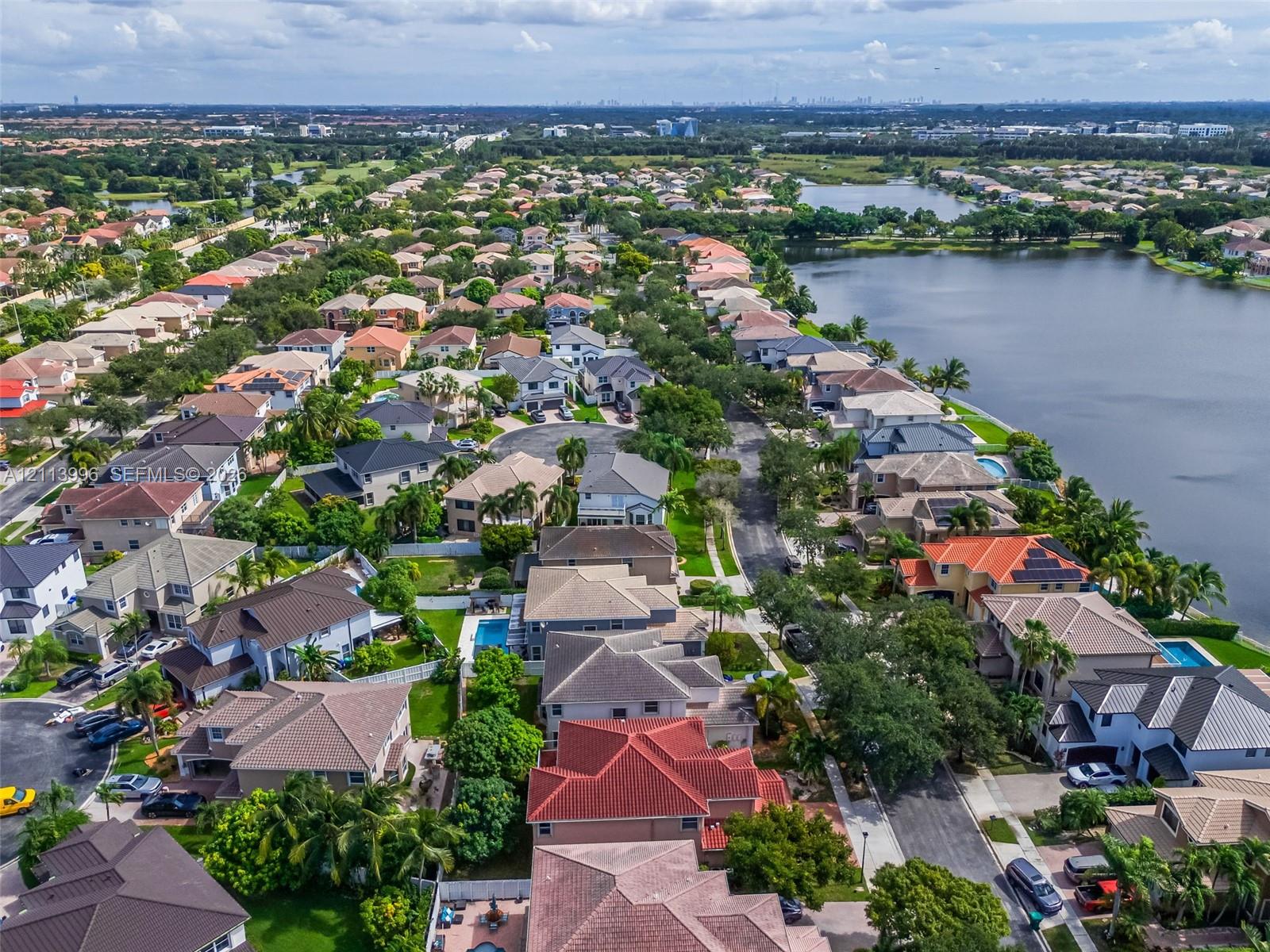 Aerial perspective featuring residential lots, paved street infrastructure, and proximity to a large water basin