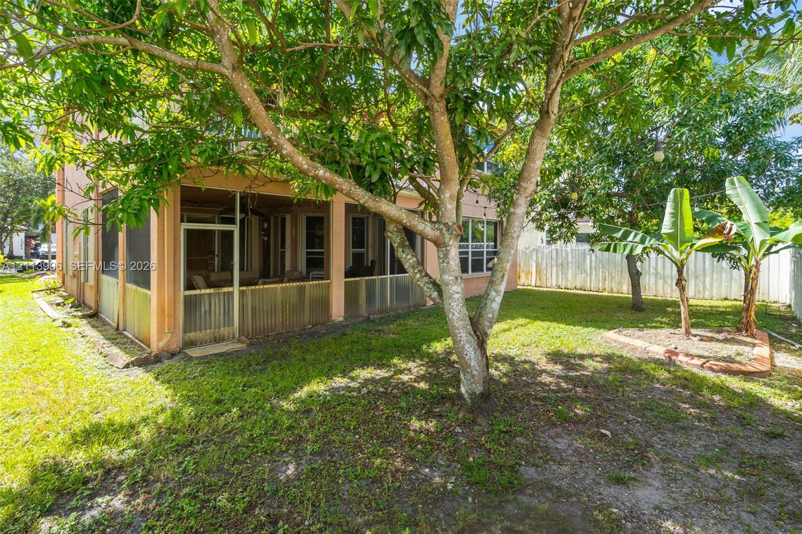 Screened-in porch featuring a concrete foundation, fenced-in backyard, and mature trees