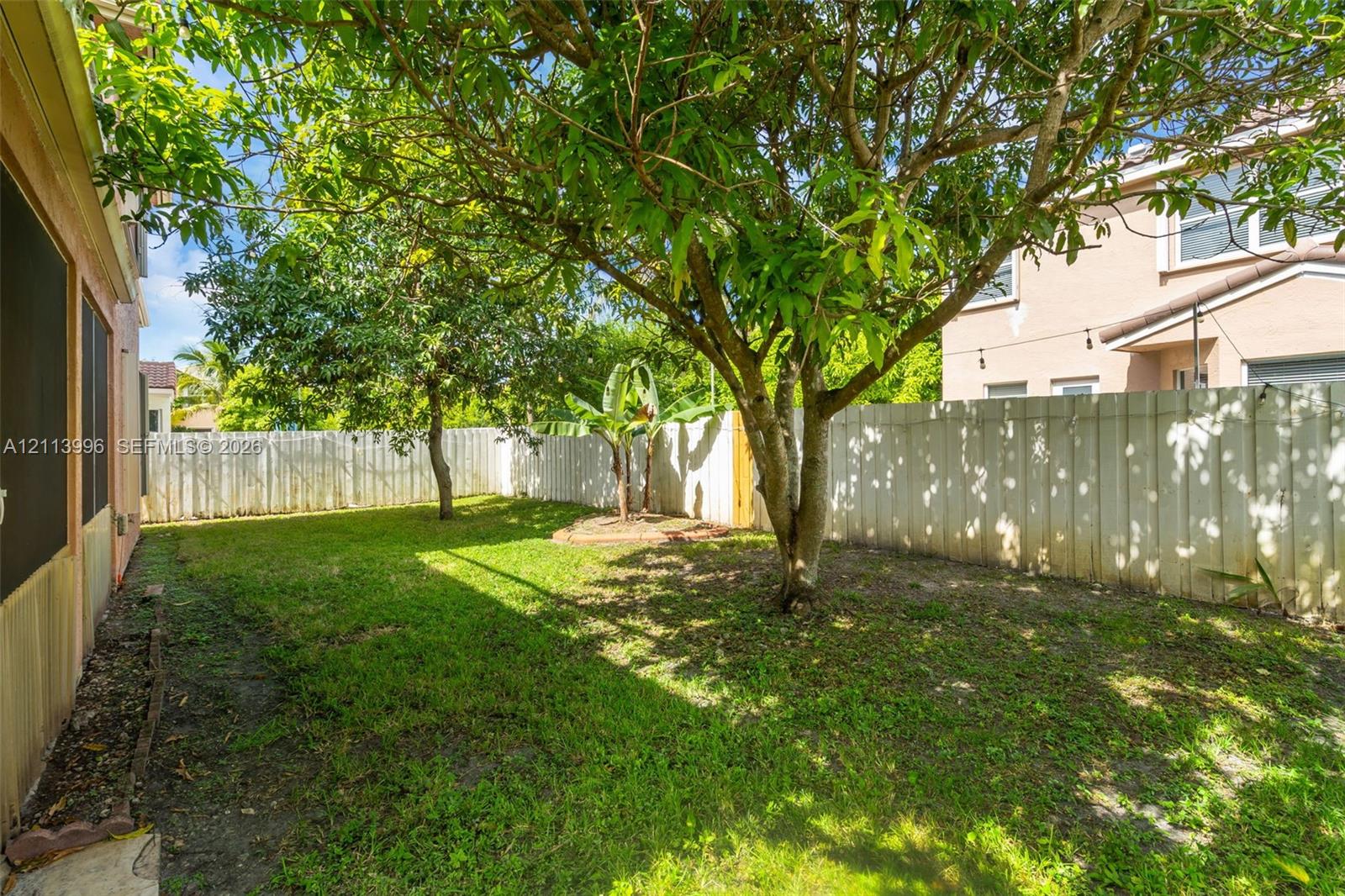 Backyard featuring privacy fencing, mature trees, and ground-level plantings