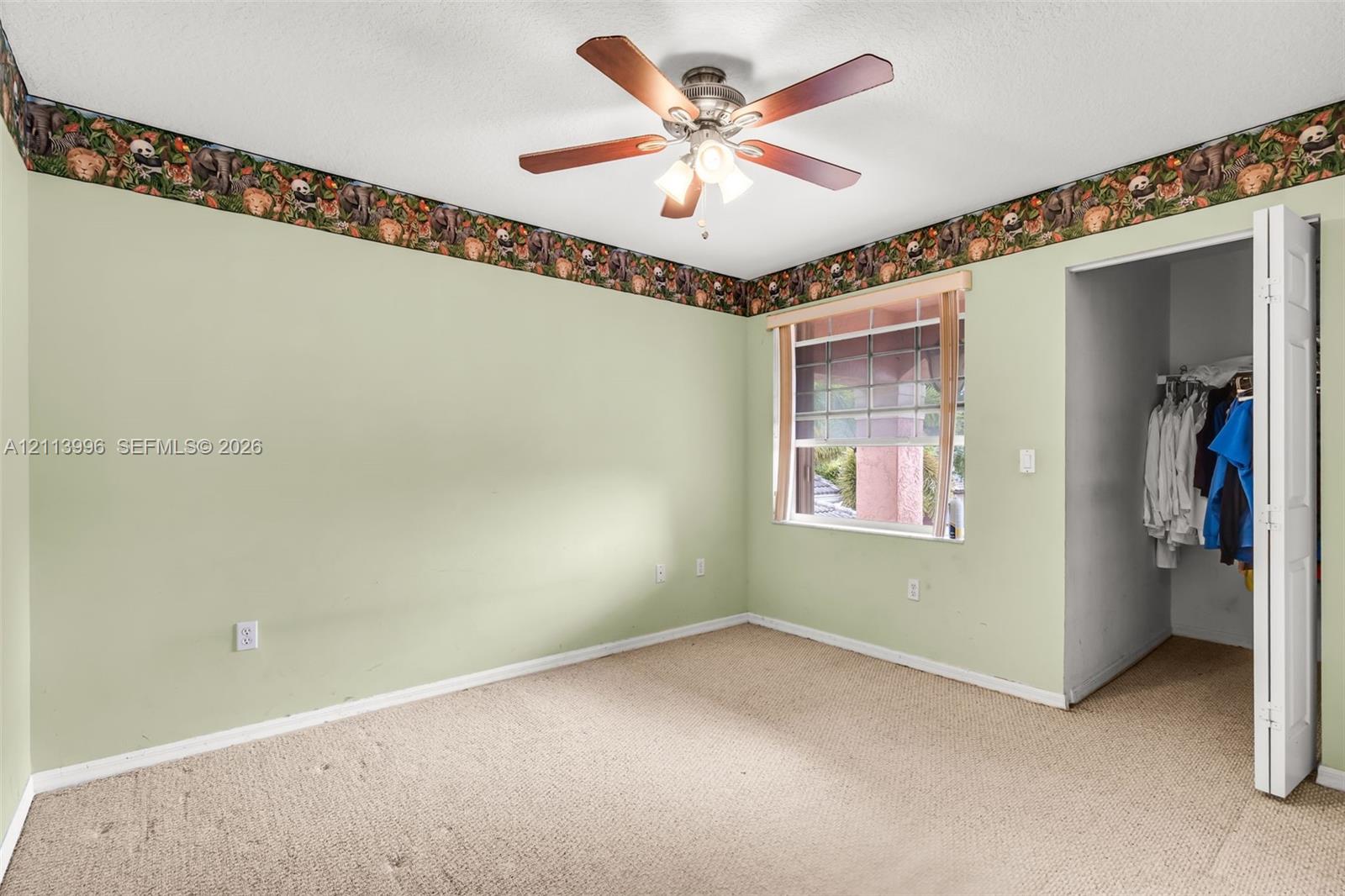 Bedroom featuring neutral wall-to-wall carpeting, a ceiling fan with integrated lighting, and a bi-fold closet door