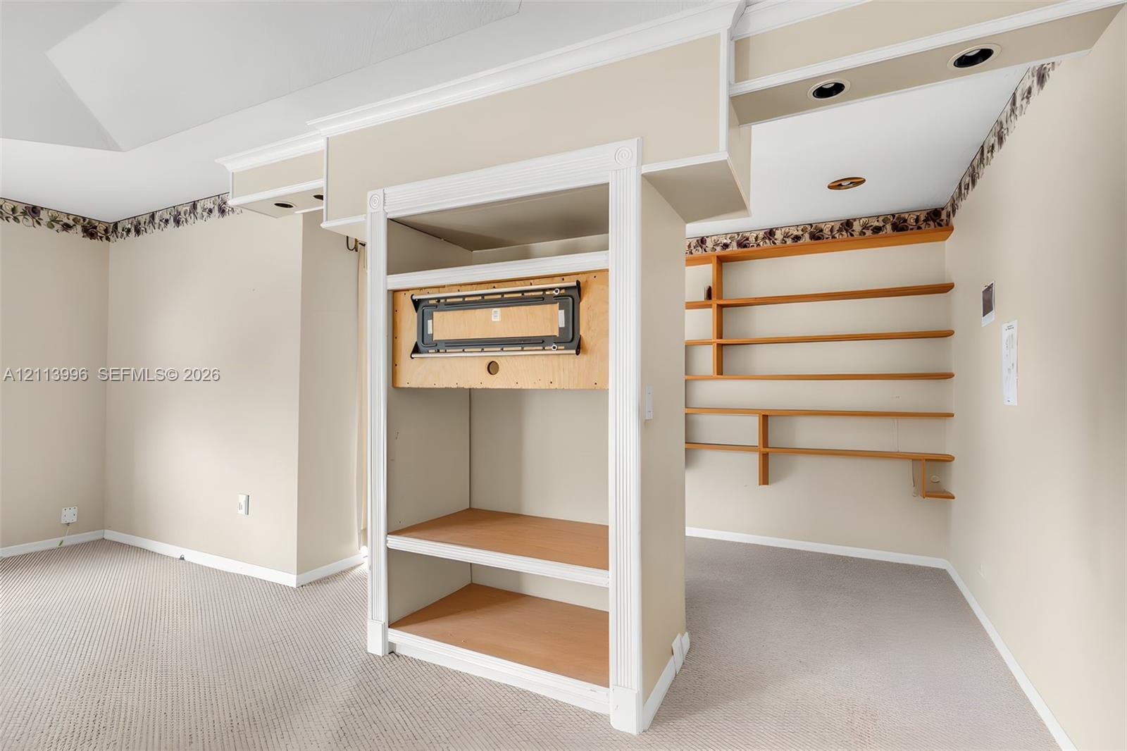 Built-in cabinetry with integrated media mount, recessed ceiling lighting, and wall-mounted shelving