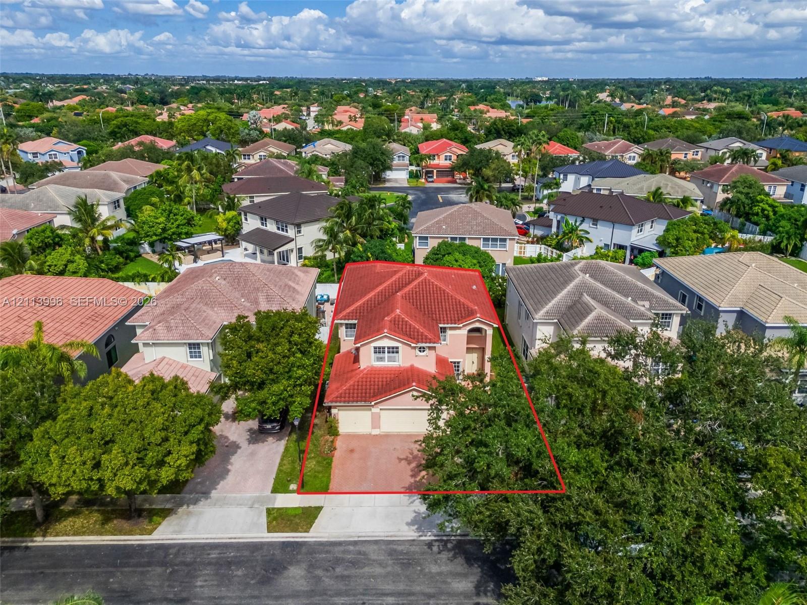 Two-story stucco exterior featuring a red tile roof, multi-gabled architectural profile, attached garage, and paved driveway
