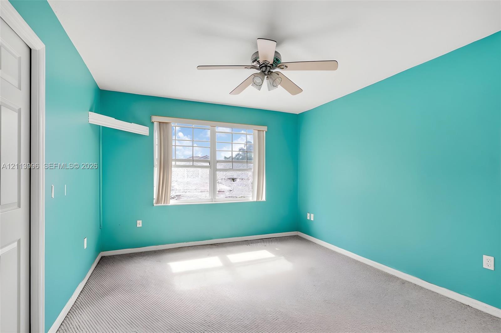Room featuring carpeted flooring, a multi-blade ceiling fan with integrated lighting, and a multi-pane window