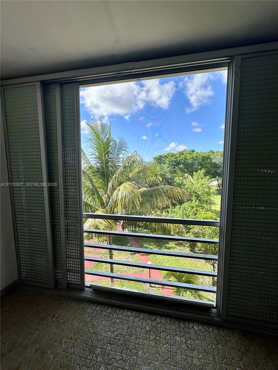 Large window featuring floor-to-ceiling sliding metal shutters, horizontal metal balcony railings, and exterior natural scenery