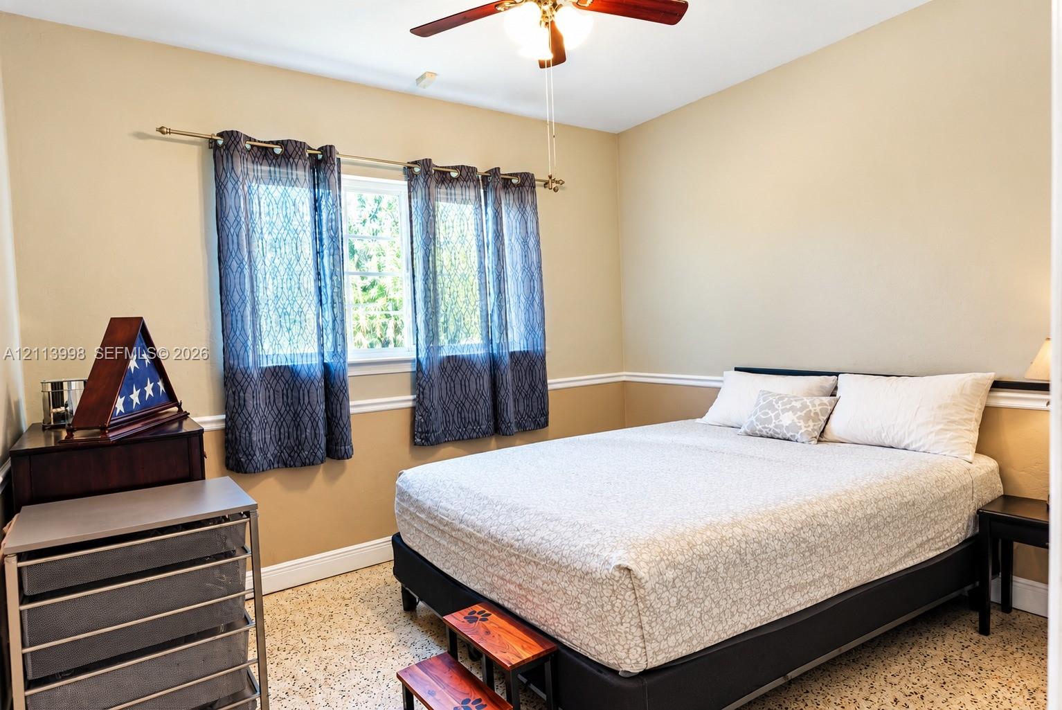 Room featuring neutral wall paint, white chair rail molding, ceiling fan with integrated lighting, and multi-pane window