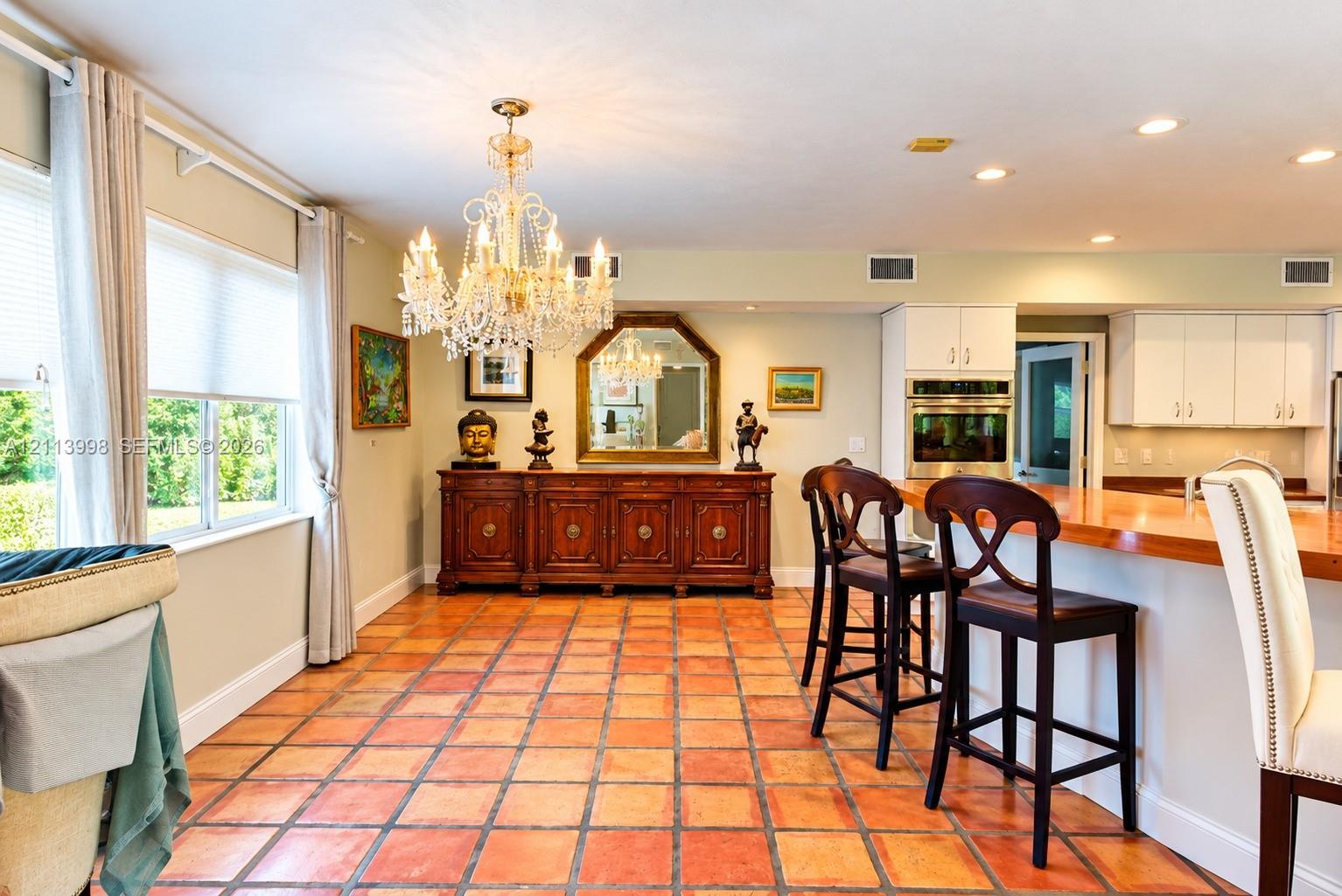 Tile flooring, tiered crystal chandelier, built-in wooden cabinetry, recessed lighting, and kitchen island with a wood countertop