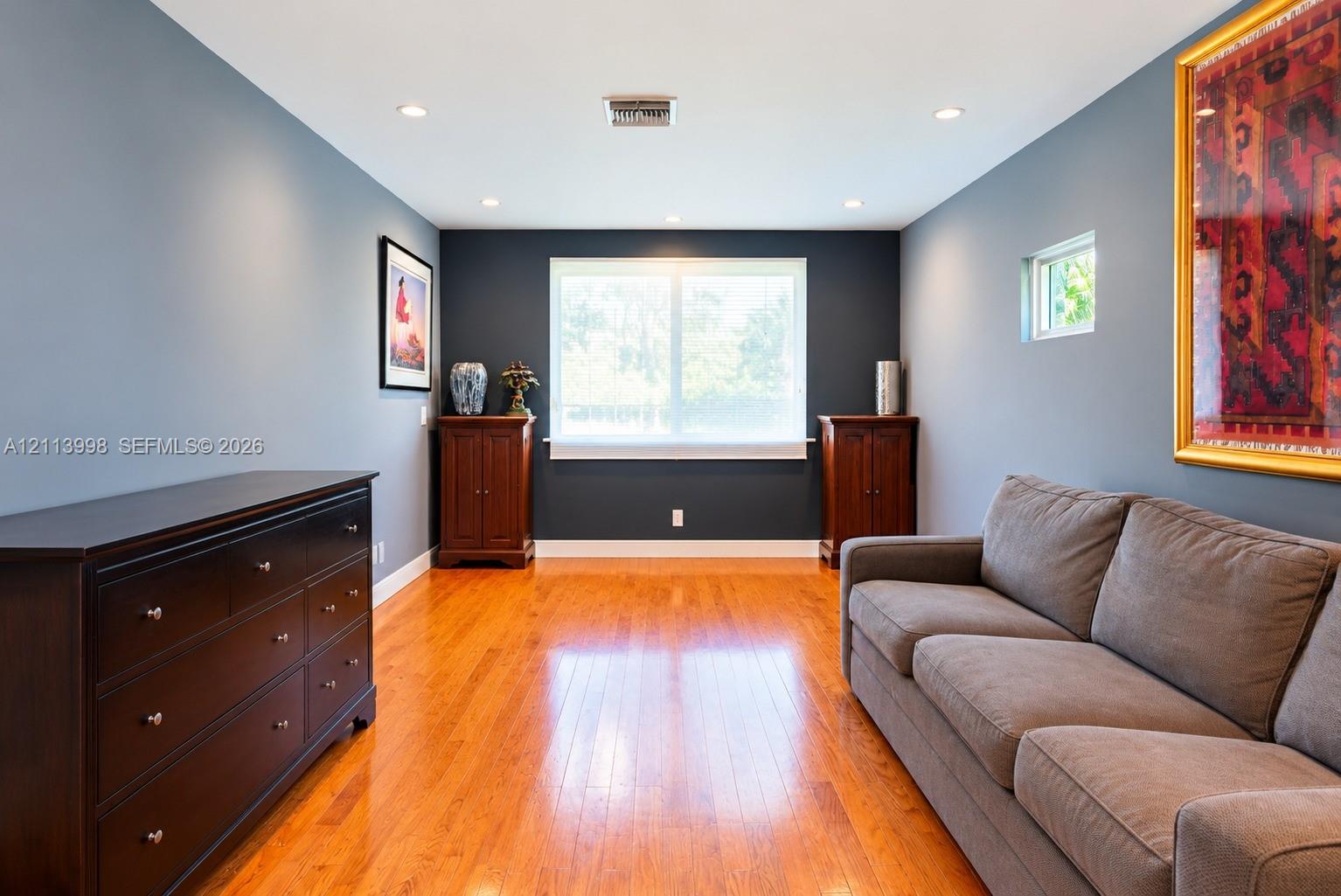 Room featuring wood-finish flooring, recessed lighting, and a neutral color palette with a dark accent wall