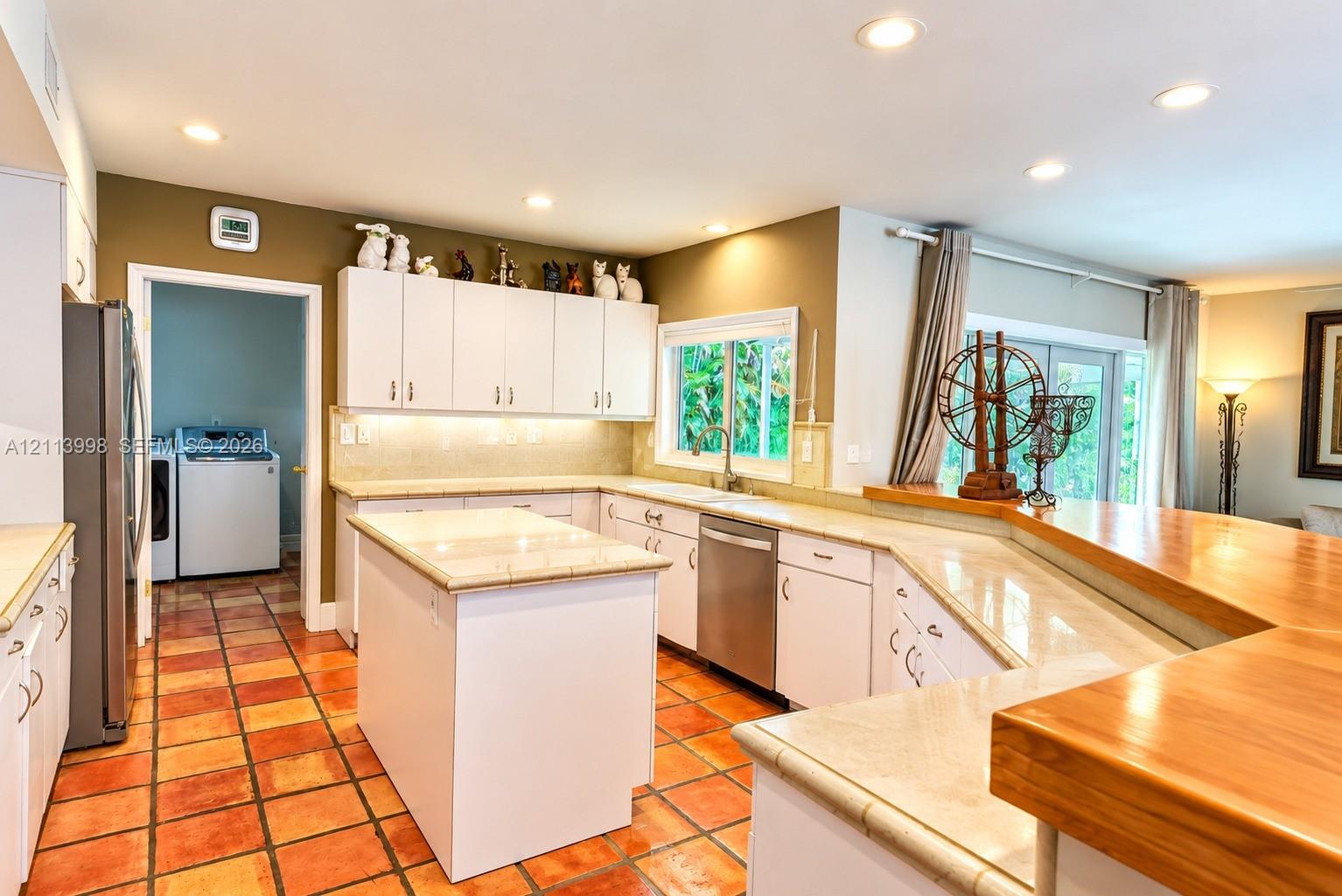 Kitchen featuring white cabinetry, center island, tile-topped counters, recessed lighting, and tile flooring
