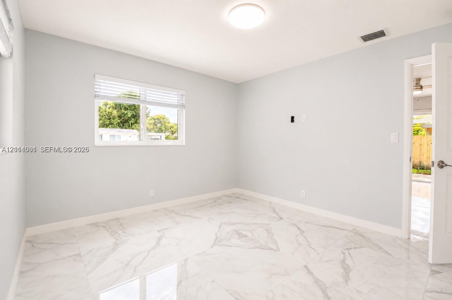 Neutral-toned room featuring large-format tile flooring with marble-style veining, recessed ceiling lighting, and a window with horizontal blinds