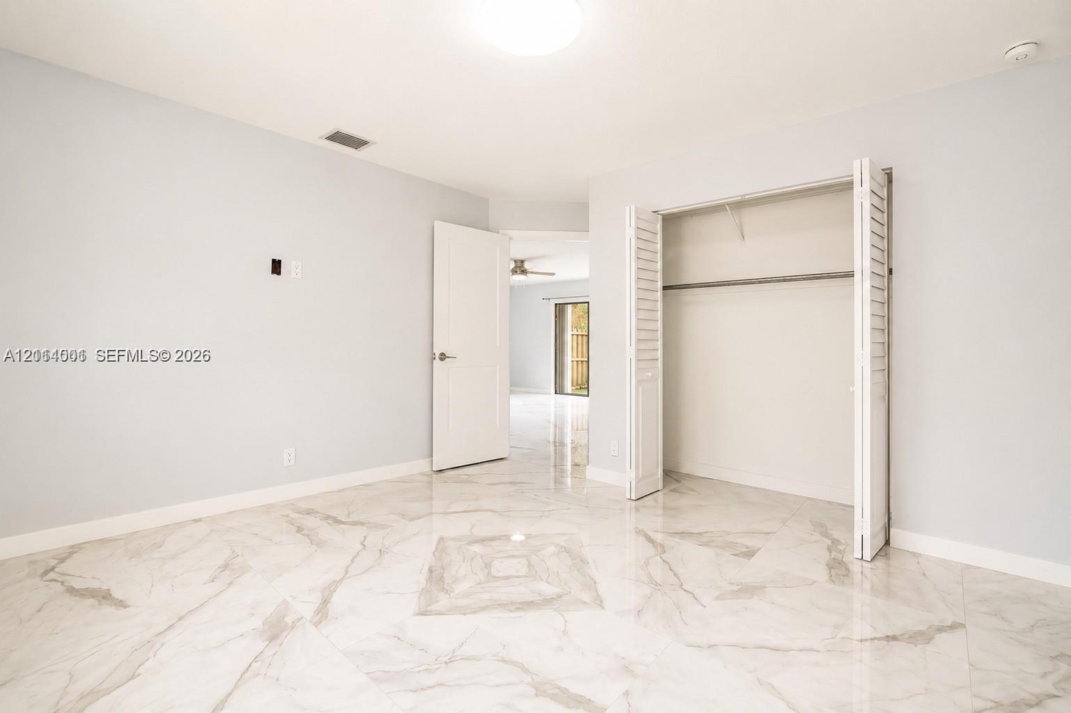 Neutral-toned interior featuring large-format polished tile flooring, white bi-fold closet doors, and a solid-core interior door