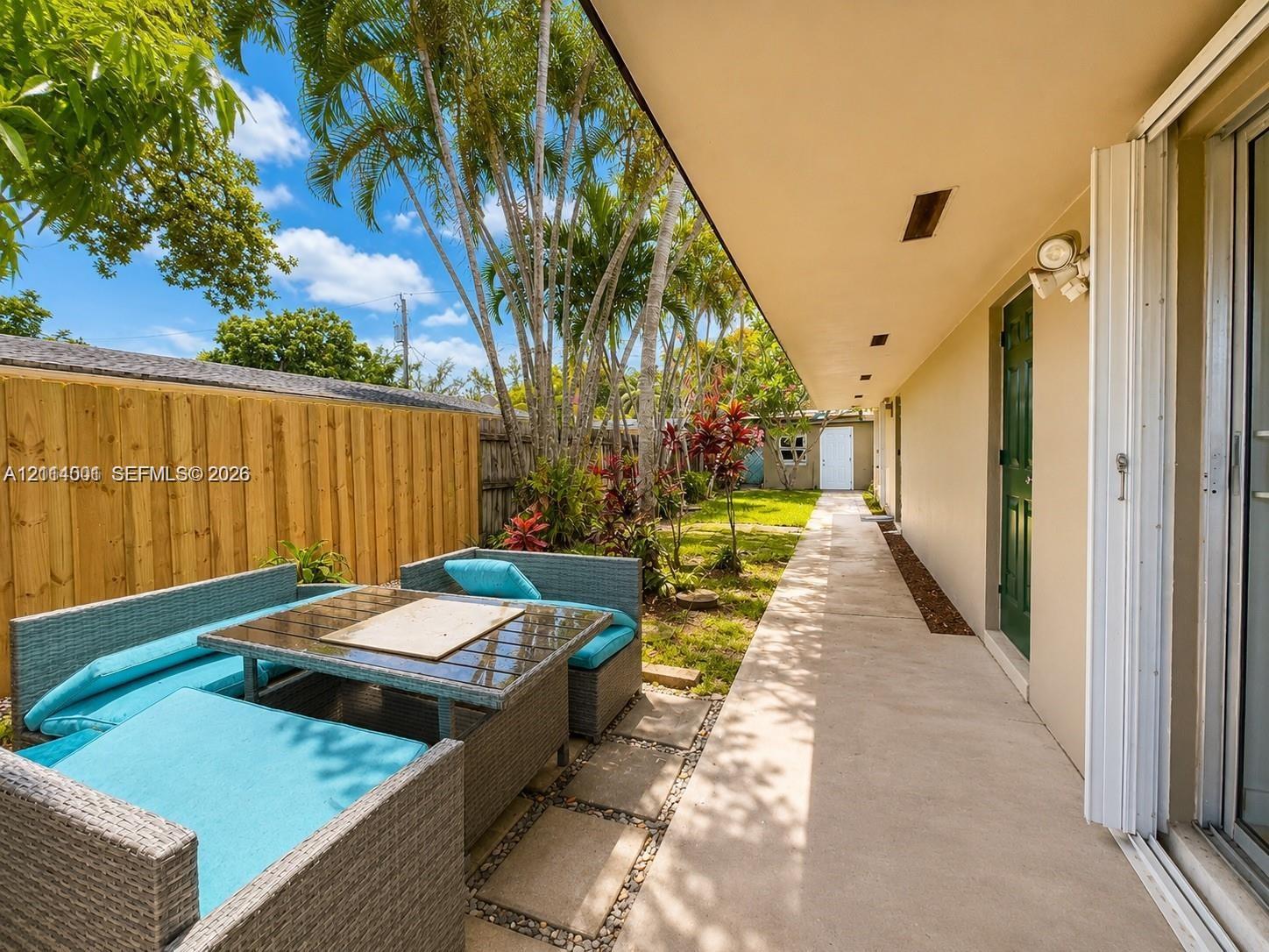 Concrete patio featuring a vertical wood fence, stone paver accents, and mature landscaping